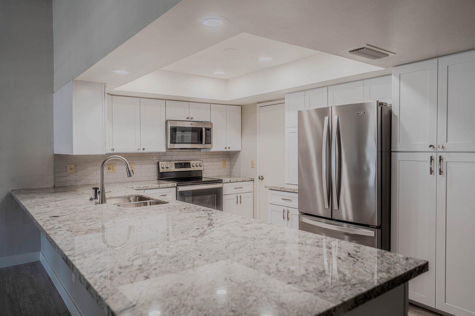 Kitchen after: white cabinets, granite counters and stainless appliances