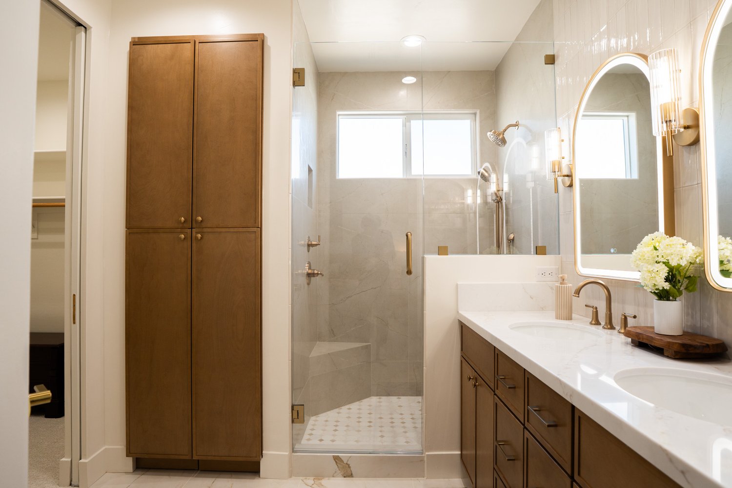 Primary bathroom after: glass walk-in marble shower, double vanity and brass fixtures